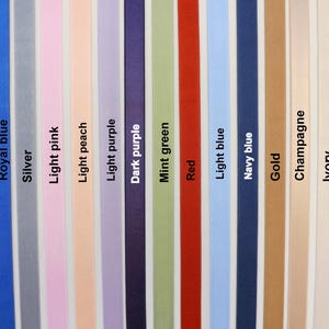 Puede incluir: Una colecci&oacute;n de quince cintas de tela verticales dispuestas una al lado de la otra en un espectro de colores que incluye negro, azul real, plata, rosa claro, melocot&oacute;n claro, morado claro, morado oscuro, verde menta, rojo, azul claro, azul marino, oro, champ&aacute;n, marfil y blanco, cada una etiquetada con su respectivo nombre de color.