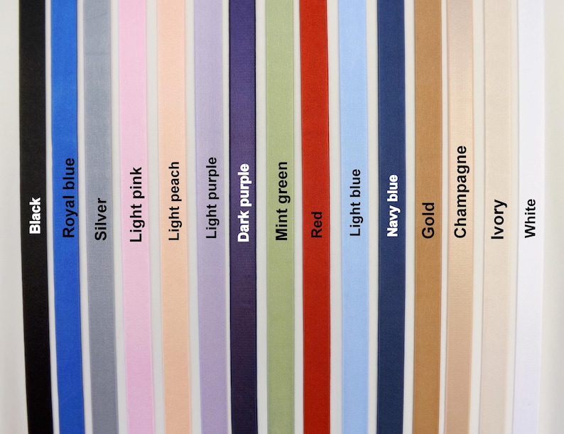 Puede incluir: Una colecci&oacute;n de quince cintas de tela verticales dispuestas una al lado de la otra en un espectro de colores que incluye negro, azul real, plata, rosa claro, melocot&oacute;n claro, morado claro, morado oscuro, verde menta, rojo, azul claro, azul marino, oro, champ&aacute;n, marfil y blanco, cada una etiquetada con su respectivo nombre de color.