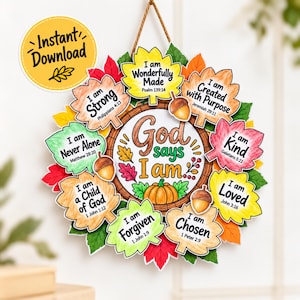 May include: A circular wall hanging featuring a central sign reading God says I am with a pumpkin illustration, surrounded by colorful paper leaves. Each leaf displays an inspirational phrase and Bible verse, accented by small brown acorns.