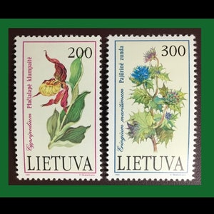 May include: Two Lithuanian postage stamps with botanical illustrations. One shows a lady slipper orchid with red and yellow petals. The other depicts a blue thistle plant. Both stamps have text in Lithuanian.