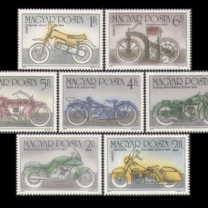 May include: A set of eight vintage Hungarian postage stamps featuring illustrations of motorcycles from different eras. The stamps are in various colors, including red, blue, green, and yellow. The stamps depict motorcycles from different manufacturers, including Fantic, Daimler, NSU, BMW, Rudge-Whitworth, Suzuki, and Harley-Davidson.