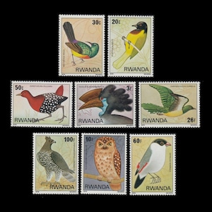 Pode incluir: Um conjunto de 10 selos postais vintage do Ruanda com ilustrações coloridas de várias aves. Os selos são retangulares e têm uma borda branca com a palavra "RWANDA" impressa em preto na parte inferior. Os selos apresentam diferentes denominações, incluindo 3f, 10f, 20c, 26f, 30c, 50c, 60f e 100f.