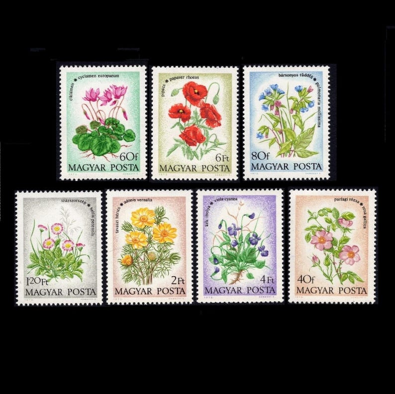 May include: A collection of seven postage stamps featuring colorful floral illustrations. The stamps showcase various flowers, including poppies, cyclamen, and violets, with text in Hungarian. The stamps are set against a black background.