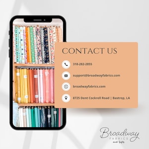 May include: A smartphone displays a fabric shop's contact information. The screen shows shelves of colorful fabric rolls. The contact card features the text "CONTACT US" with a phone number, email, website, and address for Broadway Fabrics and Gifts.
