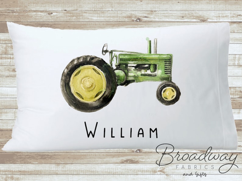 K&ouml;nnte beinhalten: Wei&szlig;er Kissenbezug mit einer Aquarell-Illustration eines gr&uuml;nen Traktors und dem Namen "William" darunter. Der Kissenbezug wird von Broadway Fabrics and Gifts hergestellt.