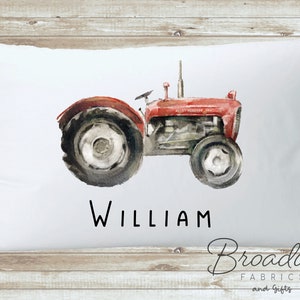 K&ouml;nnte beinhalten: Wei&szlig;er Kissenbezug mit einer Aquarell-Illustration eines roten Traktors und dem Namen "William" in Schwarz gedruckt.