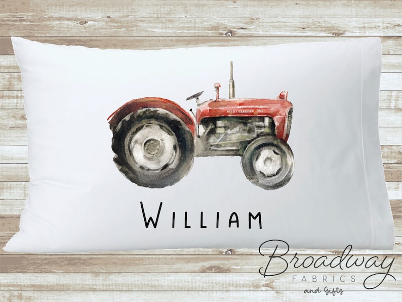 K&ouml;nnte beinhalten: Wei&szlig;er Kissenbezug mit einer Aquarell-Illustration eines roten Traktors und dem Namen "William" in Schwarz gedruckt.