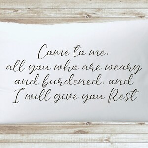 May include: White pillow with black text that reads "Come to me, all you who are weary and burdened, and I will give you Rest."