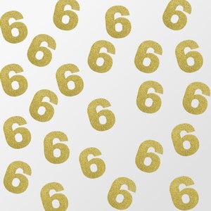 May include: A white background with gold glitter number sixes scattered across the surface.