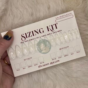 以下が含まれることがあります： バーガンディ色の文字で「SIZING KIT」と書かれた白いカード。カードには透明なネイルチップとサイズを書き込むスペースが含まれています。「FOXMOON HOLLOW」のブランド名が下部に印刷されています。