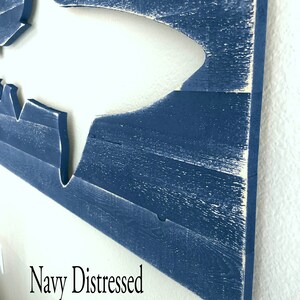 May include: A navy blue distressed wood wall art featuring a cutout of a shark. The text "Navy Distressed" is visible in the bottom left corner of the image.