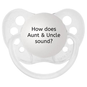 May include: A clear baby pacifier with a round, white front. The text "How does Aunt & Uncle sound?" is printed in black on the white front. The pacifier has a clear, rounded shield and a clear handle.