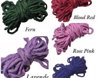 May include: An assortment of colorful macrame cord bundles in various shades. Colors include Fern, Blood Red, Rose Pink, Lavende, and Midnight. Each bundle is labeled with its respective color name. The cords are tightly wound and ready for crafting projects.