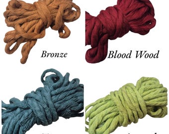 May include: Four bundles of thick, twisted cotton rope in various colors. The colors include bronze, blood wood, turquoise, and avocado. Each bundle has a label with the color name. Ideal for macrame, crafting, or home decor projects.
