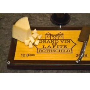 May include: A wooden serving board with the text "GRAND VIN DE LAFITE ROTHSCHILD" and "12 Blles" and "2008". The board holds a wedge of cheese and cheese cubes, with a knife and a glass of wine visible.