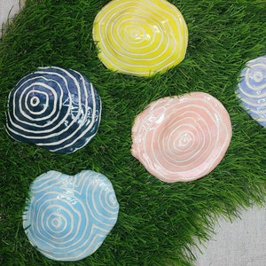 Pode incluir: Cinco  tapetes de cerâmica com um design de espiral. Os tapetes são de várias cores, incluindo amarelo, azul, rosa e branco.