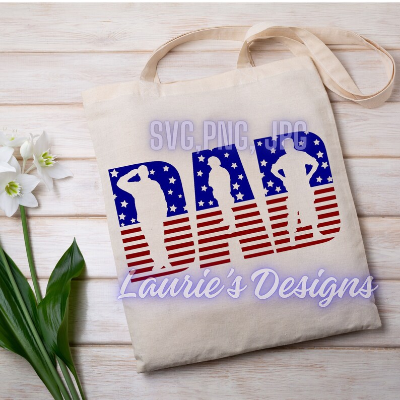 May include: A white tote bag with the word "DAD" in red, white, and blue. The letters are made up of an American flag pattern with three silhouette figures of people standing in front of the flag. The text "SVG.PNG.JPG" is at the top of the bag and the text "Laurie's Designs" is at the bottom of the bag.