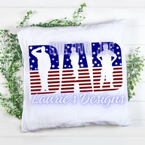 May include: A white pillow with the word "DAD" in red, white, and blue. The letters are made up of American flag stripes and stars. There are three silhouette figures of soldiers inside the letters. The text "Laurie's Designs" is below the word "DAD".