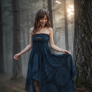May include: A strapless dark blue dress featuring a black circular mandala pattern, a high-low hemline, and a central wooden ring detail at the bodice. The garment is paired with a crown made of dark twigs and clear crystal points.