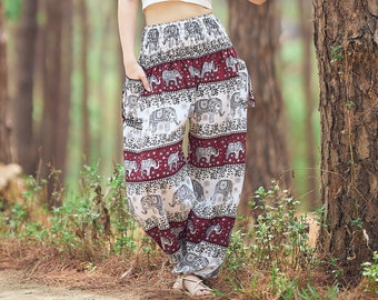 Könnte beinhalten: Weißes Crop-Top und Hose mit Elefantenmuster. Die Hose hat ein bordeauxrotes und weißes Farbschema. Das Model steht neben einem Baum in einer Waldlandschaft.