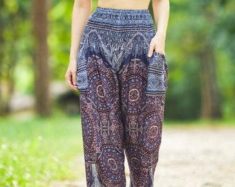May include: A woman wearing a black crop top and blue and purple patterned pants with a geometric design. She is standing on a path in a forest.