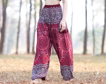 Könnte beinhalten: Eine Frau trägt ein schwarzes Crop-Top und eine rote, gemusterte Hose mit Mandala-Design und steht in einem Wald.