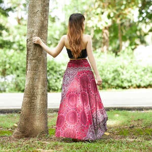 Pode incluir: Uma mulher vestindo uma saia maxi estampada em vermelho e branco com um top preto. Ela est&aacute; em p&eacute; ao lado de uma &aacute;rvore em um parque.