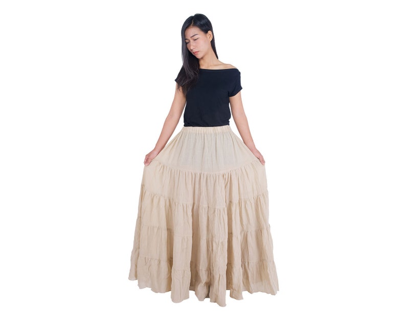 May include: A beige tiered maxi skirt with a ruffled hem. The skirt is made of a lightweight fabric and has a relaxed fit.