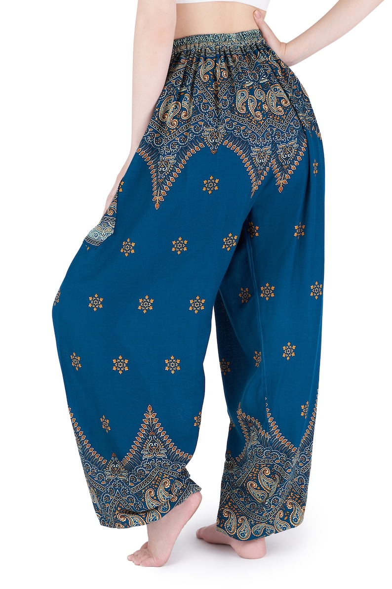 K&ouml;nnte beinhalten: Weit geschnittene Hose in Blaugr&uuml;n mit elastischem Bund, verziert mit einem sich wiederholenden Paisley-Muster in Gold und Dunkelblau an Taille und Saum, erg&auml;nzt durch ein verstreutes kleines Goldstern-Motiv auf den Beinen.