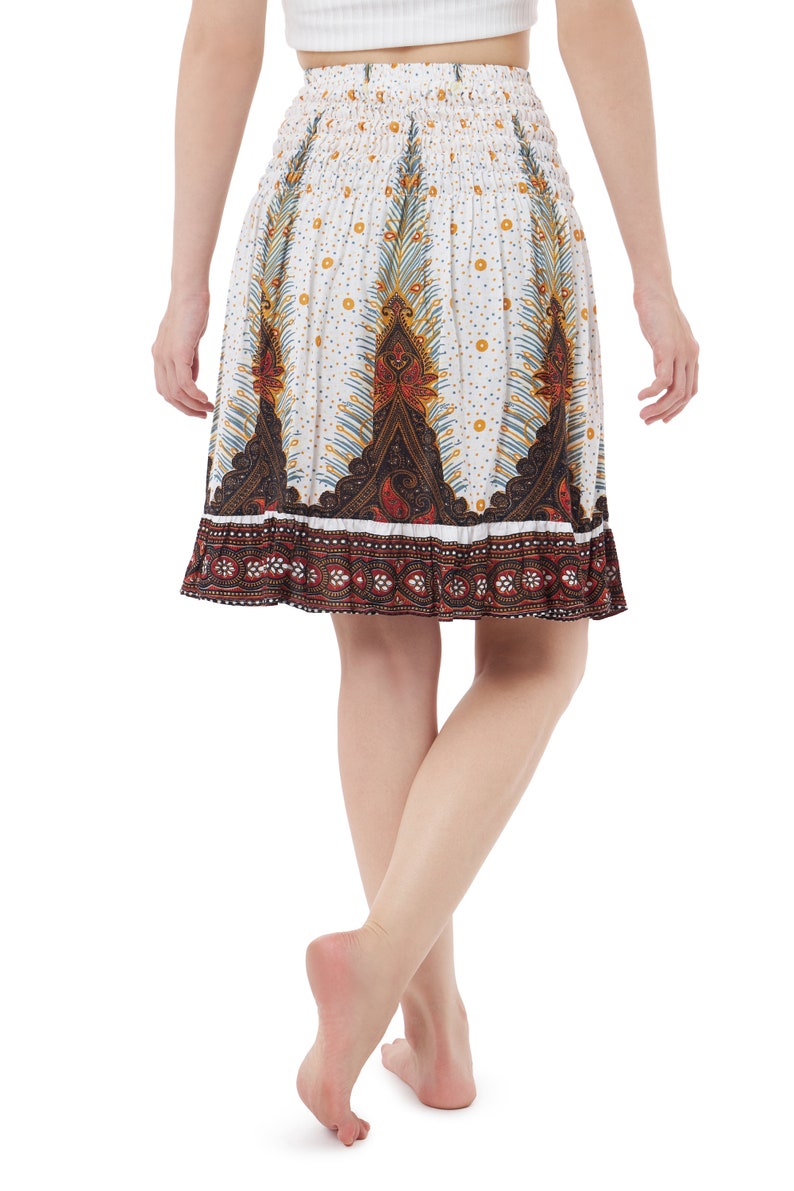 K&ouml;nnte beinhalten: Ein wei&szlig;er Rock mit einem bunten Paisley-Muster und einem braunen elastischen Bund. Der Rock ist knielang und hat einen R&uuml;schen-Saum.