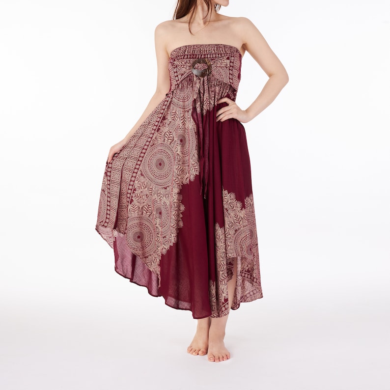 Puede incluir: Un vestido maxi sin tirantes de color burdeos con estampado de mandala dorado y blanco. El vestido tiene una cintura ajustada y un dobladillo alto-bajo.