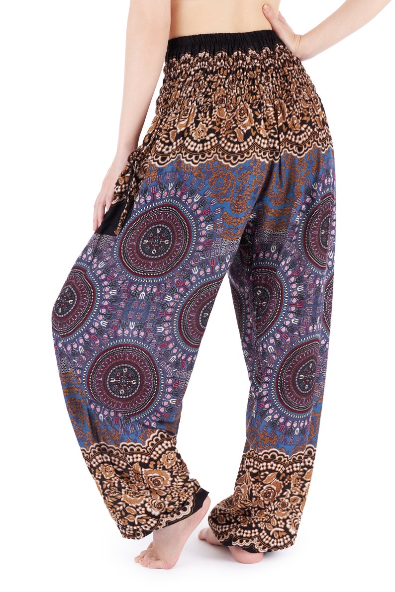 May include: Loose-fitting, patterned pants with a black elastic waistband. The pants feature a blue background with circular mandala-like designs in shades of purple, red, and pink. The cuffs and waistband have a brown floral pattern.