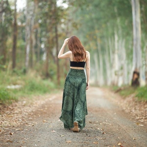 Op de afbeelding: Een zwarte crop top met spaghettibandjes gecombineerd met een lange, zwierige groene rok met een donker, ingewikkeld cirkelvormig mandalapatroon en een brede, gesmokte elastische tailleband die hoog in de taille zit voor een losse pasvorm.