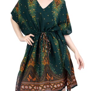 K&ouml;nnte beinhalten: Ein gr&uuml;nes, orangefarbenes und goldenes Kaftan mit V-Ausschnitt und kurzen &Auml;rmeln. Der Kaftan hat eine Kordeltaille und einen Paisley-Druck.