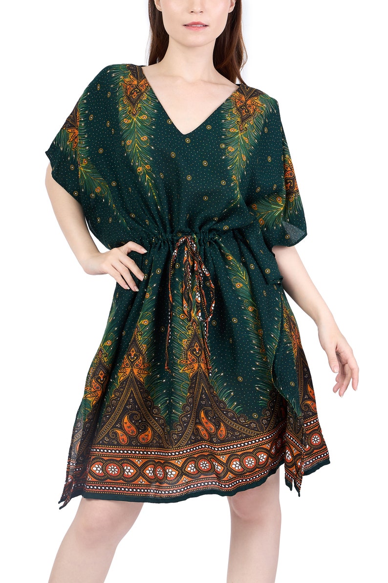 K&ouml;nnte beinhalten: Ein gr&uuml;nes, orangefarbenes und goldenes Kaftan mit V-Ausschnitt und kurzen &Auml;rmeln. Der Kaftan hat eine Kordeltaille und einen Paisley-Druck.