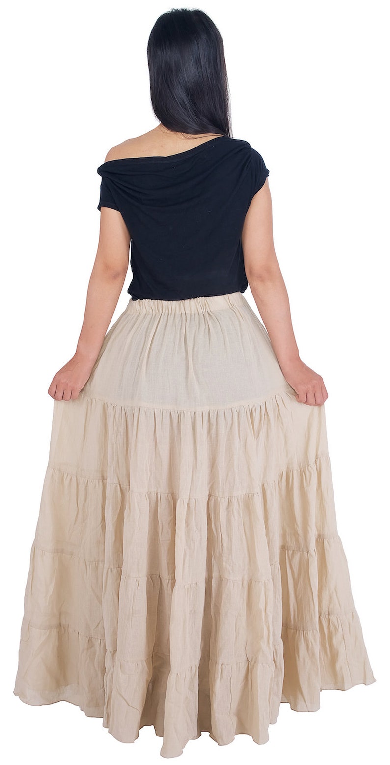 May include: A beige tiered maxi skirt with a gathered elastic waistband. The skirt is made of a lightweight, flowy fabric.