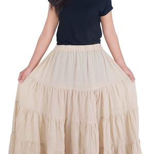 May include: A beige tiered maxi skirt with a black off-the-shoulder top.