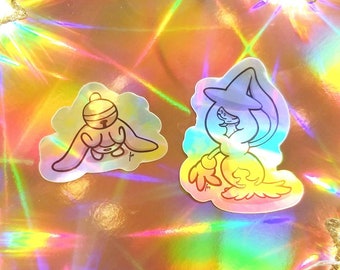 Puede incluir: Dos pegatinas holográficas iridiscentes con personajes de dibujos animados. La primera pegatina es un personaje azul y amarillo con un sombrero de bruja. La segunda pegatina es un personaje gris y blanco con un casco y alas.