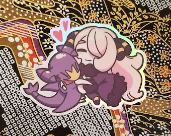 Puede incluir: Pegatina holográfica con dos personajes de dibujos animados abrazándose, con dos corazones rosas encima. Un personaje es morado con una corona dorada, y el otro es rosa claro con detalles negros y dorados. La pegatina tiene un acabado brillante e iridiscente.