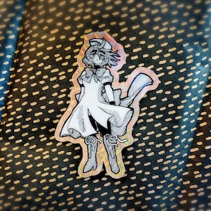 May include: A black and white illustration of a girl wearing a white dress and a hat. The illustration is printed on a holographic sticker.