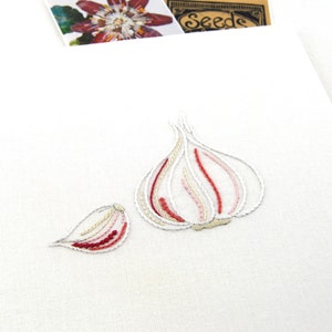 May include: Embroidered white canvas with a red and white garlic clove and a smaller red and white garlic clove.