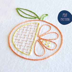 May include: Embroidered orange design with a green stem and leaves. The orange is divided into two sections, one with a yellow and pink checkered pattern and the other with a flower design.