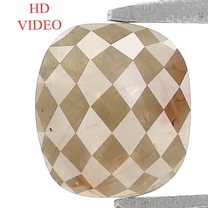 Pode incluir: Uma gema com corte almofada com um padrão xadrez, segurada por pinças. A gema apresenta facetas marrons claras e escuras alternadas, com o texto "HD VIDEO" no canto superior esquerdo.