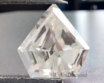 Könnte beinhalten: Ein klarer, facettierter, quadratischer Diamant-Edelstein, der mit einer Pinzette gehalten wird. Der Diamant ist in einer einzigartigen, geometrischen Form geschliffen.