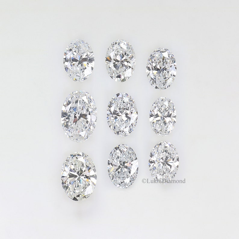 May include: Nine oval-shaped diamonds arranged in three rows on a white background.  The diamonds are clear and sparkly.