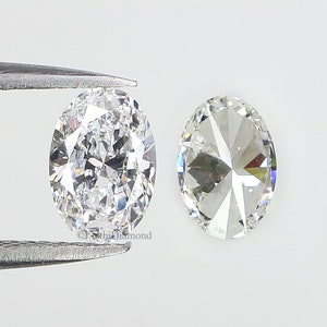 May include: Two oval-shaped diamonds, one held by tweezers, with a clear, brilliant cut and a high degree of sparkle.