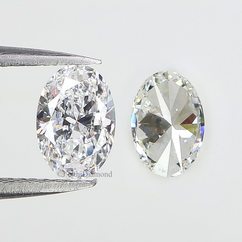 May include: Two oval-shaped diamonds, one held by tweezers, with a clear, brilliant cut and a high degree of sparkle.