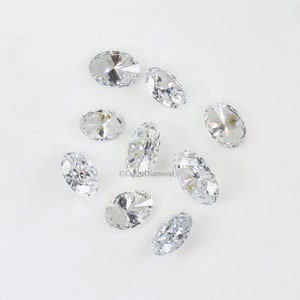 May include: A group of ten oval-shaped, clear, faceted gemstones on a white background.