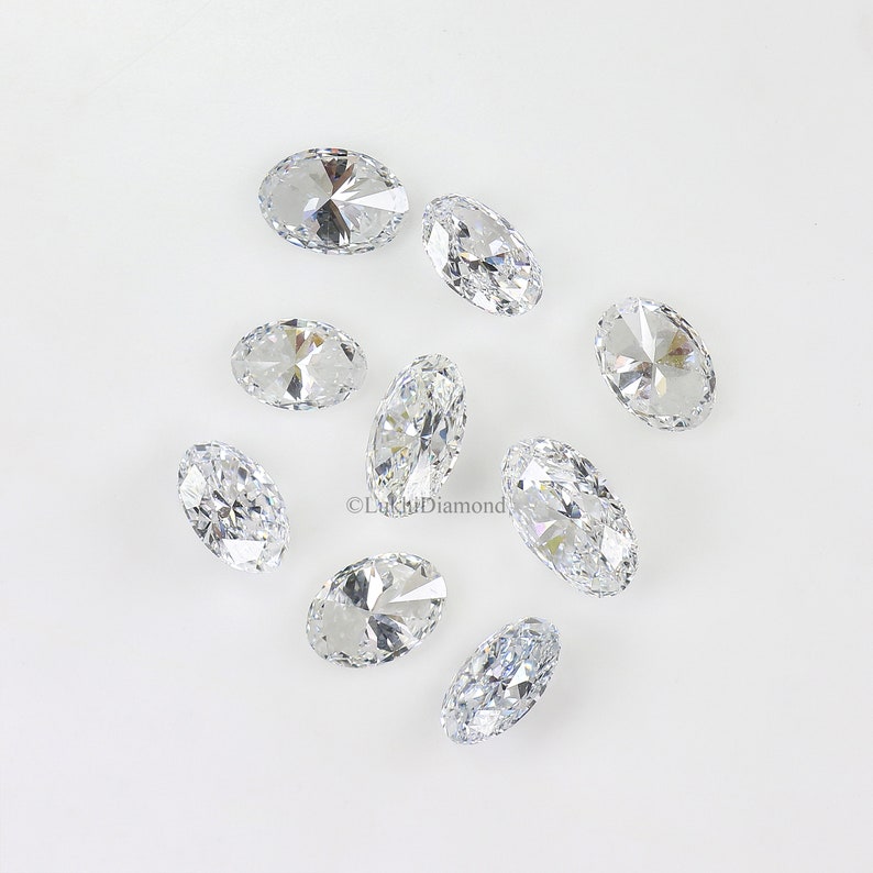 May include: A group of ten oval-shaped, clear, faceted gemstones on a white background.
