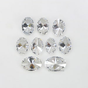 May include: Eight clear oval-shaped gemstones with a faceted design. The gemstones are arranged in two rows on a white background.